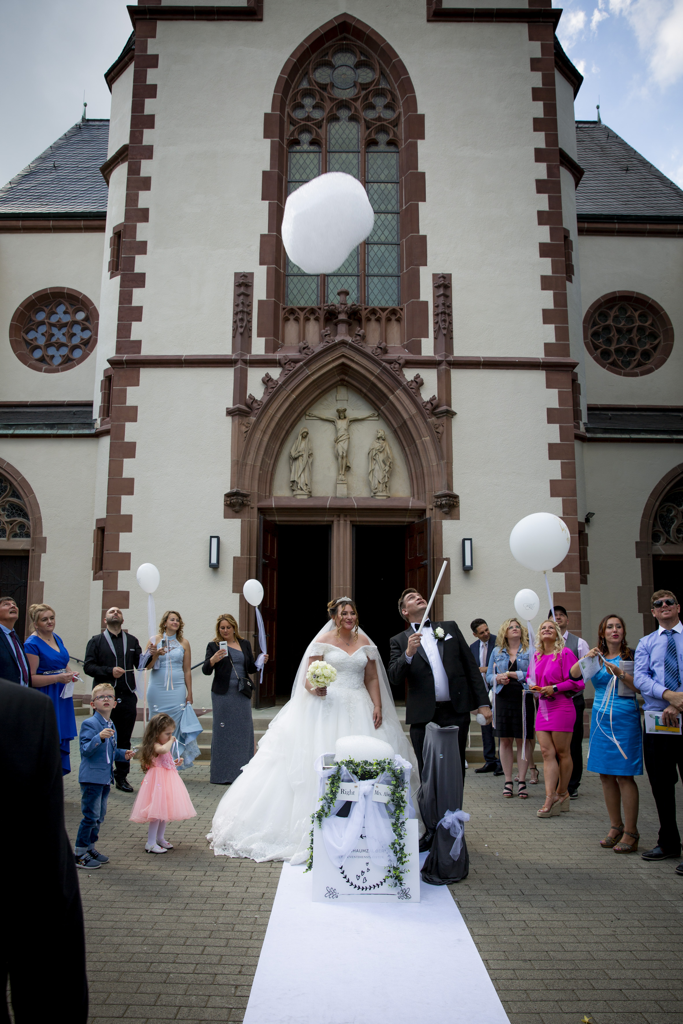Start eines Schaumherzens vor einer Kirche mit Gästen und Brautpaar